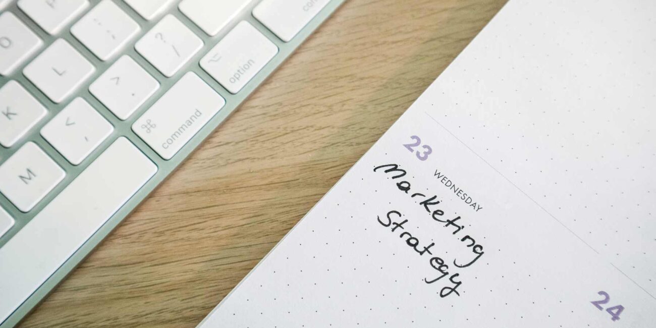 The Fractional CMO - "Marketing Strategy" written on a desktop calendar next to a keyboard